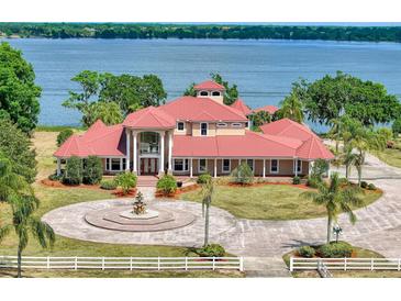 Stunning waterfront home with red tile roof, circular driveway, and lush landscaping at 11715 Taylor Rd, Thonotosassa, FL 33592