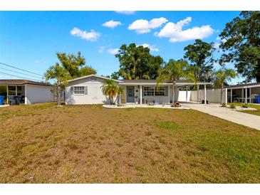 Charming single-story home features a well-maintained front yard, mature trees, and a covered carport at 14917 Philmore Rd, Tampa, FL 33613