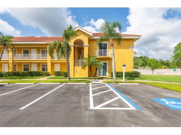 Inviting yellow condominium building with a red tile roof, palm trees, and accessible parking at 21012 Picasso Ct # 201, Land O Lakes, FL 34637