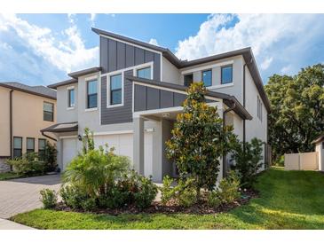 Charming two-story home featuring a well-manicured lawn and a beautifully landscaped front yard with mature trees at 21590 Violet Periwinkle Dr, Land O Lakes, FL 34637