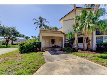 Two-story exterior with a covered carport, lush tropical landscaping, and a well-maintained lawn at 2600 Forest Run Ct, Clearwater, FL 33761