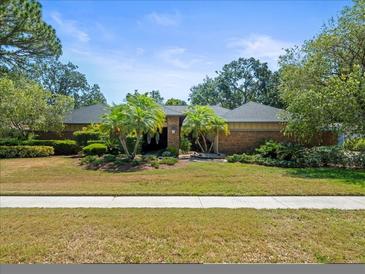 Charming single-story brick home with lush landscaping, vibrant green grass, and well-manicured palm trees at 3309 Westmoreland Dr, Tampa, FL 33618