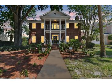 Elegant two-story brick home featuring a grand porch with classic columns and a well-manicured front yard at 4309 W Robin Ln, Tampa, FL 33609