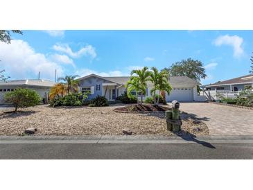 Charming coastal home with manicured landscaping, featuring palm trees and a brick-paved driveway at 6321 Balboa Ln, Apollo Beach, FL 33572