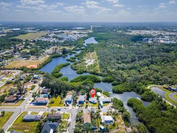An aerial view shows the property nestled on a waterfront lot surrounded by lush greenery at 6908 11Th E Ave, Palmetto, FL 34221