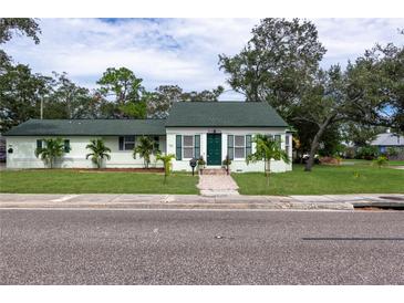 Charming single-story home with a green roof, shutters, landscaped yard, and welcoming brick pathway at 701 38Th N Ave, St Petersburg, FL 33704