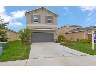 Two-story home featuring a neutral facade, gray shutters, a two-car garage, and a well-maintained front lawn at 5068 Little Stream Ln, Wesley Chapel, FL 33545