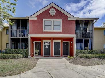 Charming two-story condo with a red stucco facade, screened balconies, and well-maintained landscaping at 10509 Waterview Ct, Tampa, FL 33615