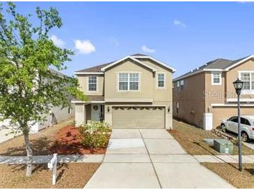 Traditional two-story home with neutral color palette, landscaping, and attached two-car garage at 12028 Citrus Leaf Dr, Gibsonton, FL 33534