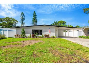 Charming one-story home featuring a lush green lawn and covered carport, plus eye-catching curb appeal at 219 80Th Ne Ave, St Petersburg, FL 33702