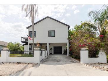 Modern two-story home featuring a gated driveway, lush landscaping, and an inviting facade at 7404 Bay Dr, Tampa, FL 33635