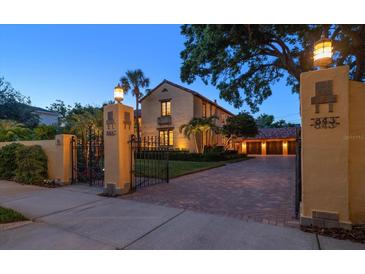 Elegant, gated home with a brick driveway, mature landscaping, and warm exterior lighting at dusk at 843 17Th N Ave, St Petersburg, FL 33704