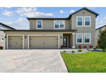 Charming two-story home featuring a three-car garage and well-manicured landscaping at 9287 Crescent Ray Dr, Wesley Chapel, FL 33545