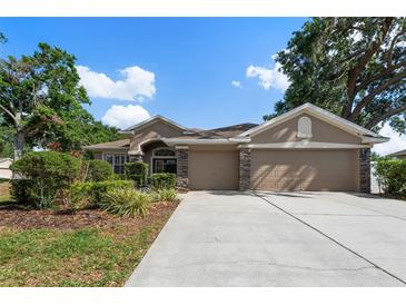 Beautiful one story home with a stone facade and a well manicured lawn with mature trees in a lush green setting at 2402 Blue Stone Ct, Valrico, FL 33594