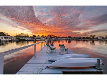 Waterfront home featuring a private dock with seating and boat storage under a beautiful sunset sky at 2487 W Bay Isle Se Dr, St Petersburg, FL 33705