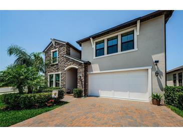 Charming two-story home with a paver driveway, a stone facade, and a two-car garage at 2653 Longleaf Pine Pt, New Port Richey, FL 34655