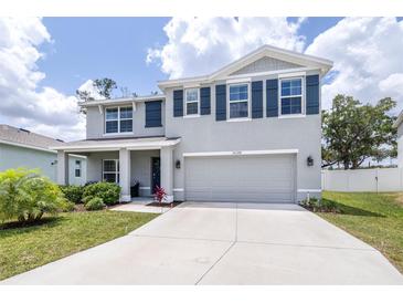 Two-story home featuring gray stucco, dark shutters, an attached two-car garage, and well-maintained landscaping at 36398 Spanish Rose Dr, Dade City, FL 33525
