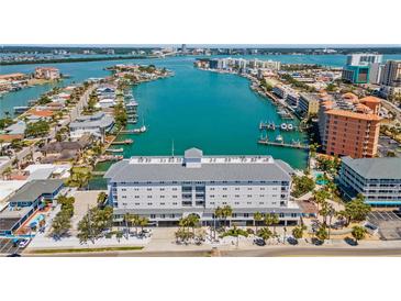 Stunning aerial view of waterfront condo building with boat docks and city skyline in the background at 445 Hamden Dr # 502, Clearwater Beach, FL 33767