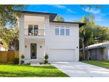 Modern two-story home featuring a balcony, manicured lawn, and a two-car garage at 116 W Stanley St, Tampa, FL 33604