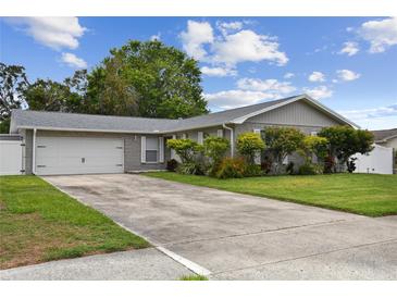 Charming single-story home with a well-manicured lawn and a long driveway leading to the garage at 1812 Teakwood Ln, Dunedin, FL 34698
