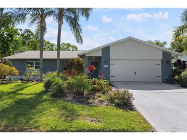 Charming home exterior with mature landscaping, palm trees, and a two-car garage at 2810 Doone Cir, Palm Harbor, FL 34684