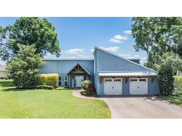 Stunning blue home featuring a well manicured lawn, attractive landscaping, and a two car garage at 3938 Lake Joyce Dr, Land O Lakes, FL 34639