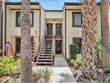 Charming condo exterior features a stairwell with tropical landscaping and a light-yellow facade at 404 Moorings Cove Dr # 404, Tarpon Springs, FL 34689