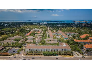 Wide aerial view of a multi-building residential complex with lush landscaping near coastal waters and distant cityscape at 1216 S Missouri Ave # 108, Clearwater, FL 33756