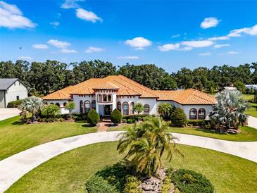 Stunning Mediterranean-style home with a circular driveway, lush landscaping, and a terracotta roof at 304 Hawk Talon Dr, Lithia, FL 33547