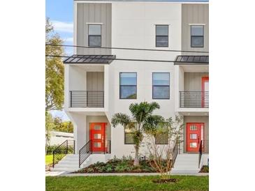 Modern townhome showcases clean lines, black framed windows, balcony, and vibrant red doors at 6904 S Macdill Ave # 1, Tampa, FL 33611