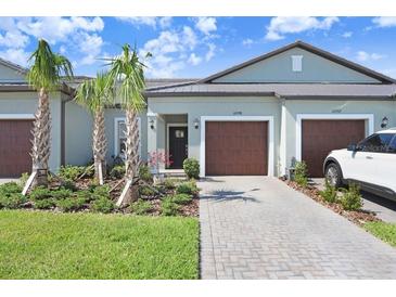 Charming villa featuring a well maintained front yard and an attached garage at 10998 Gable Dig Loop, San Antonio, FL 33576