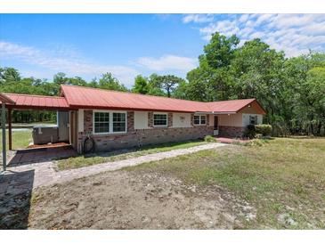 Front exterior view featuring red roof, brick accents, and walkway at 7095 South St, Webster, FL 33597