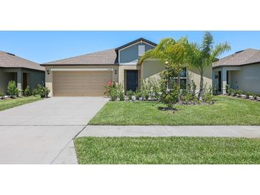 Charming single-story home with a well-manicured lawn, tropical landscaping, and attached two-car garage at 35029 Brackett Bnd, Zephyrhills, FL 33541