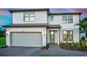 Charming two-story home with white siding, a gray roof, an attached garage, and landscaped yard at 5953 Bluestar Ct, Lakewood Ranch, FL 34211