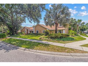 Charming one-story home showcasing a well-manicured lawn, mature trees, and lush landscaping at 6407 E 112Th Ave, Temple Terrace, FL 33617