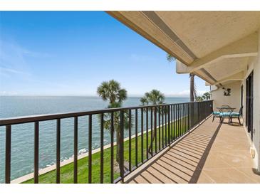 Relax on the tiled balcony with metal railings and a seating area, overlooking the lush lawn and ocean view at 7540 Sunshine Skyway S Ln # 219, St Petersburg, FL 33711