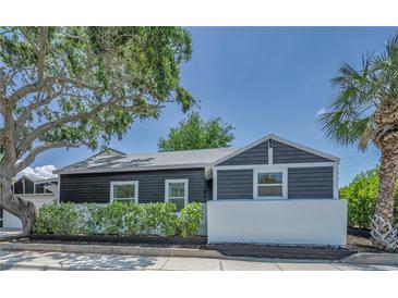 Charming home featuring dark siding, a white accent wall, and mature trees in a landscaped front yard at 847 Highland N St, St Petersburg, FL 33701