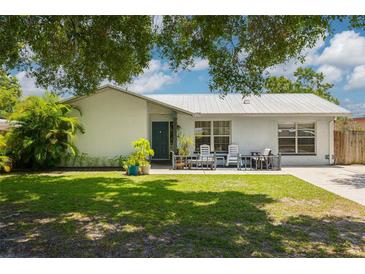 Charming single-story home featuring a metal roof, cozy front porch, and lush green lawn at 2153 Catalina N Dr, Clearwater, FL 33763
