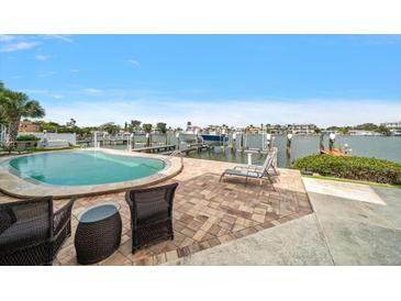 Inviting pool with waterfront views, dock, brick patio with wicker furniture, and serene landscape at 2511 Bay Blvd # B, Indian Rocks Beach, FL 33785