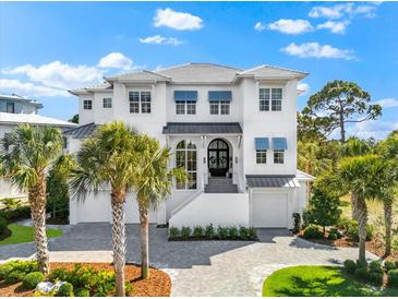 Elegant two-story home featuring a white exterior, gray roof, blue awnings, and professionally landscaped front yard at 885 Seaview Cir # 20, Crystal Beach, FL 34681
