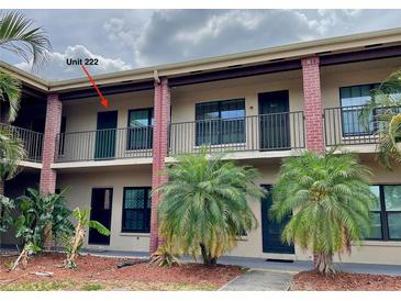 Two-story building featuring brick and tan exterior, black railings, and tropical landscaping in front at 1020 85Th N Ave # 222, St Petersburg, FL 33702