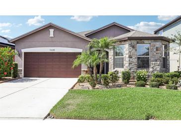 Charming single Gathering home featuring a stone facade accent and a well-maintained lawn with palms at 11688 Brighton Knoll Loop, Riverview, FL 33579