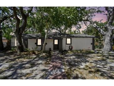 Charming single-story home with mature trees and a welcoming entrance with a gray door at 1247 21St St, Sarasota, FL 34234
