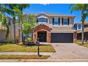 Charming two-story home featuring a stone-accented entry, dark-stained garage door, and palm tree-lined front yard at 12935 Solola Way, Trinity, FL 34655