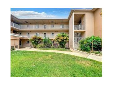 Multi-story condo building featuring maintained green spaces with shrubs and open-air walkways on a partly cloudy day at 2737 Enterprise E Rd # 122, Clearwater, FL 33759