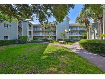 Inviting condo building with lush landscaping, a sidewalk, and palm trees creates an appealing outdoor space at 330 Promenade Dr # 206, Dunedin, FL 34698