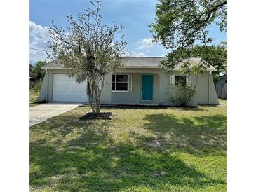 Charming single-story home featuring a well-maintained lawn, front yard tree, and a bright blue front door at 9230 Wood Dr, Hudson, FL 34667