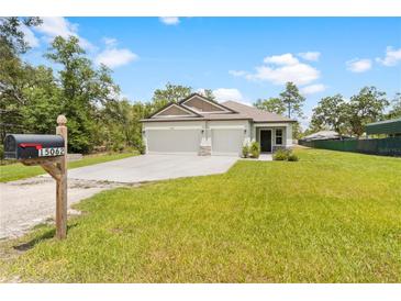 Charming single-story home featuring a 3-car garage, manicured lawn, and mailbox with house number at 15062 Hummingbird Rd, Weeki Wachee, FL 34614