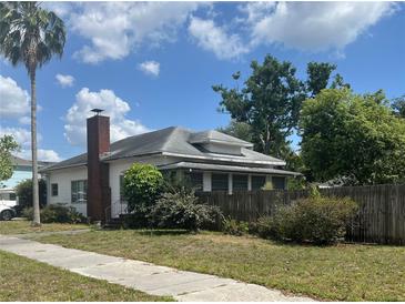 Quaint single-story home featuring a red brick chimney, well-maintained lawn, and charming curb appeal at 3210 W North B St, Tampa, FL 33609