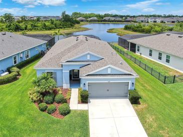 Aerial view of a blue single-story home with a spacious backyard, a lake view, and a two-car garage at 5539 Silver Sun Dr, Apollo Beach, FL 33572